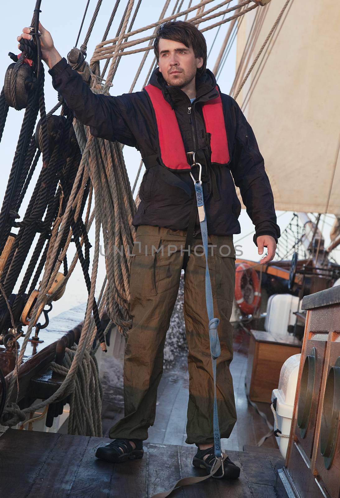 Young sailor onboard with sails behind him