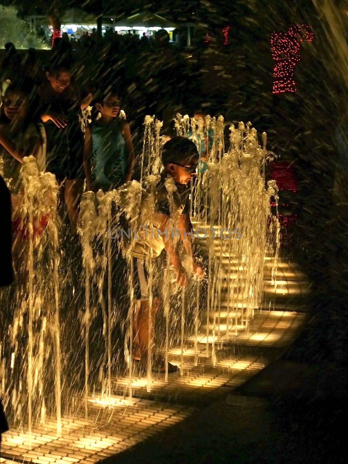 PERU, Lima: A child plays with water in a fountain as dozens of people assist to light and water show in front of the largest water wall of the world just inaugurated in the Park of the Reserve, Lima, Peru on January 15, 2016. 