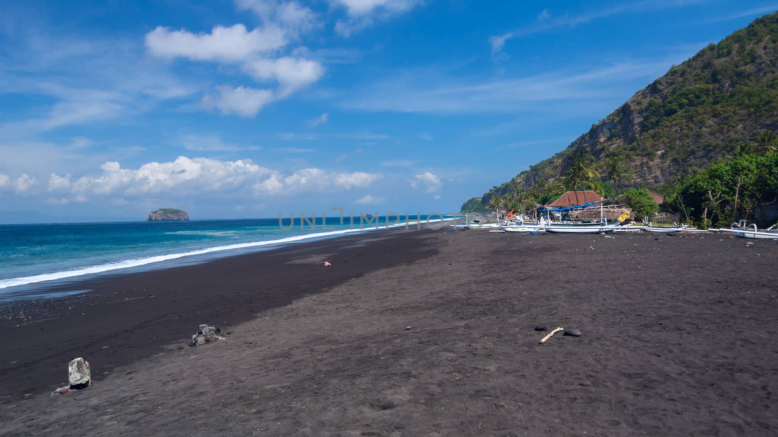 Junks on the beach of black sand on the island of Bali in Indonesia. Summer sunny day.