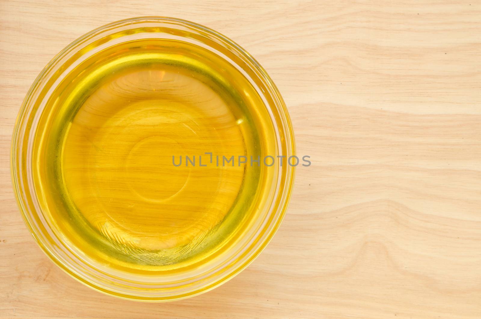 Vegetable oil in glass cup on wooden background.