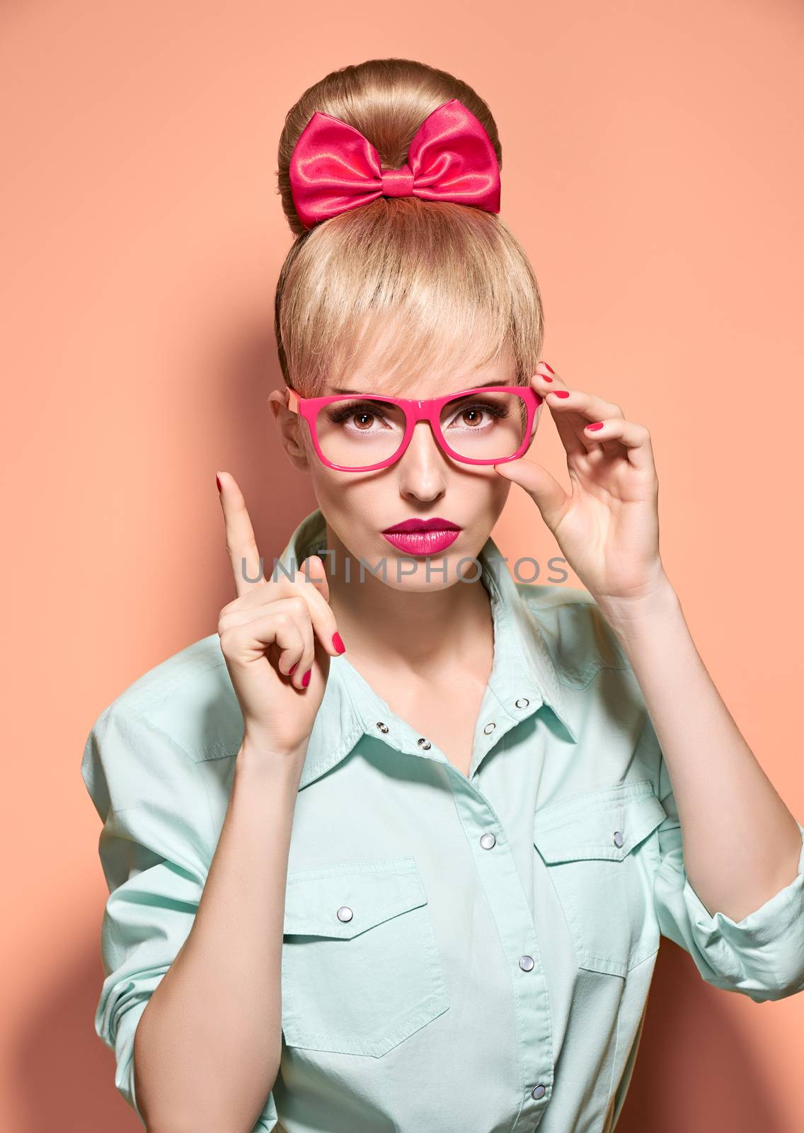 Beauty fashion nerdy woman in stylish glasses thinking, idea. Attractive pretty funny blonde girl smiling. Confidence, success, Pinup hairstyle bow makeup. Unusual playful, expression.Vintage, on pink