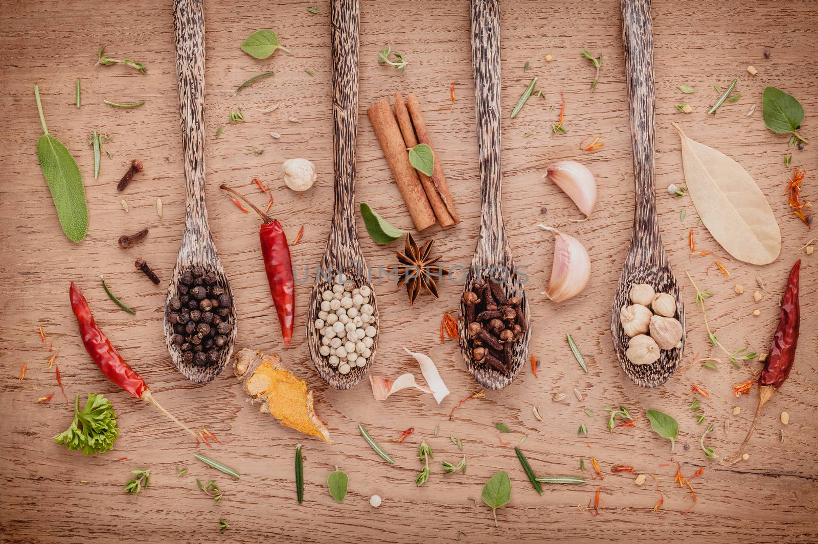 Assorted of spices  in wooden spoon  black pepper ,white pepper, black mustard,yellow mustard,fenugreek,cumin ,curry powder ,paprika and  fennel seeds on teak wood background.