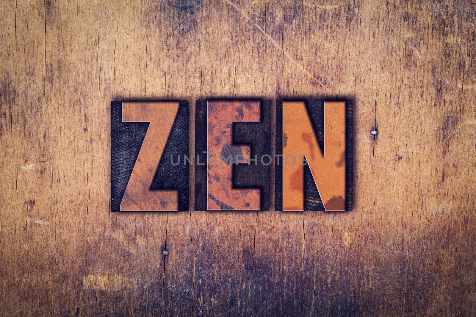 The word "Zen" written in dirty vintage letterpress type on a aged wooden background.