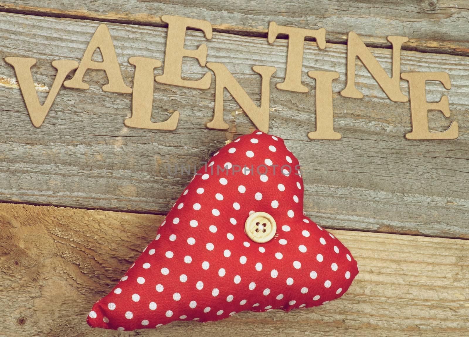 Valentine Theme Background with Cardboard Words and Handmade Textile Red Polka Dot Heart closeup on Rustic Wooden background