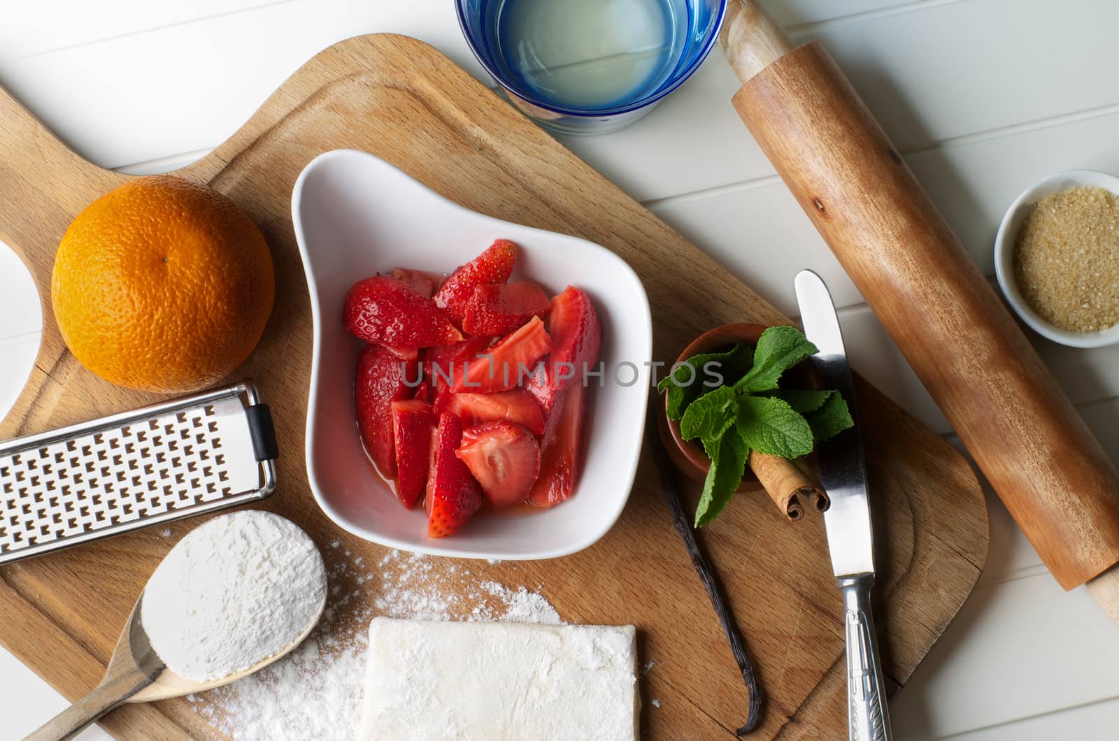 Preparing Homemade Puff Pastry Stuffed Strawberries and Orange Peel with Kitchen Equipment and Ingredients closeup on Wooden Cutting Board