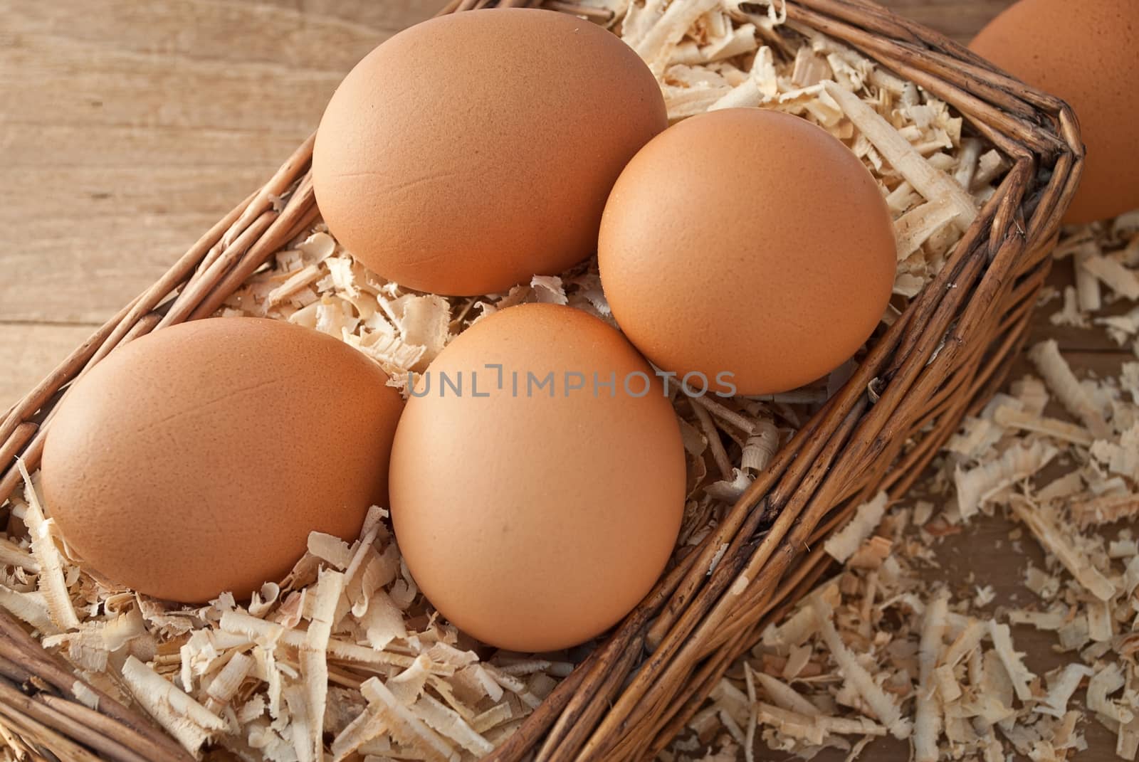 Egg on sawdust with old basket over on wooden background 