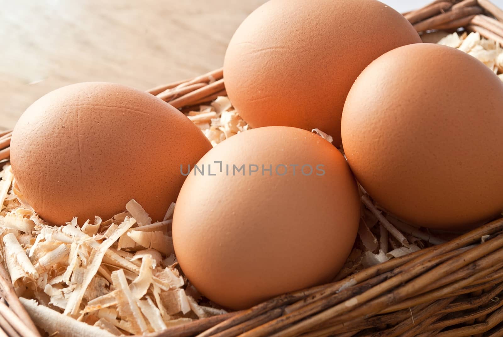 Egg on sawdust with old basket over on wooden background 