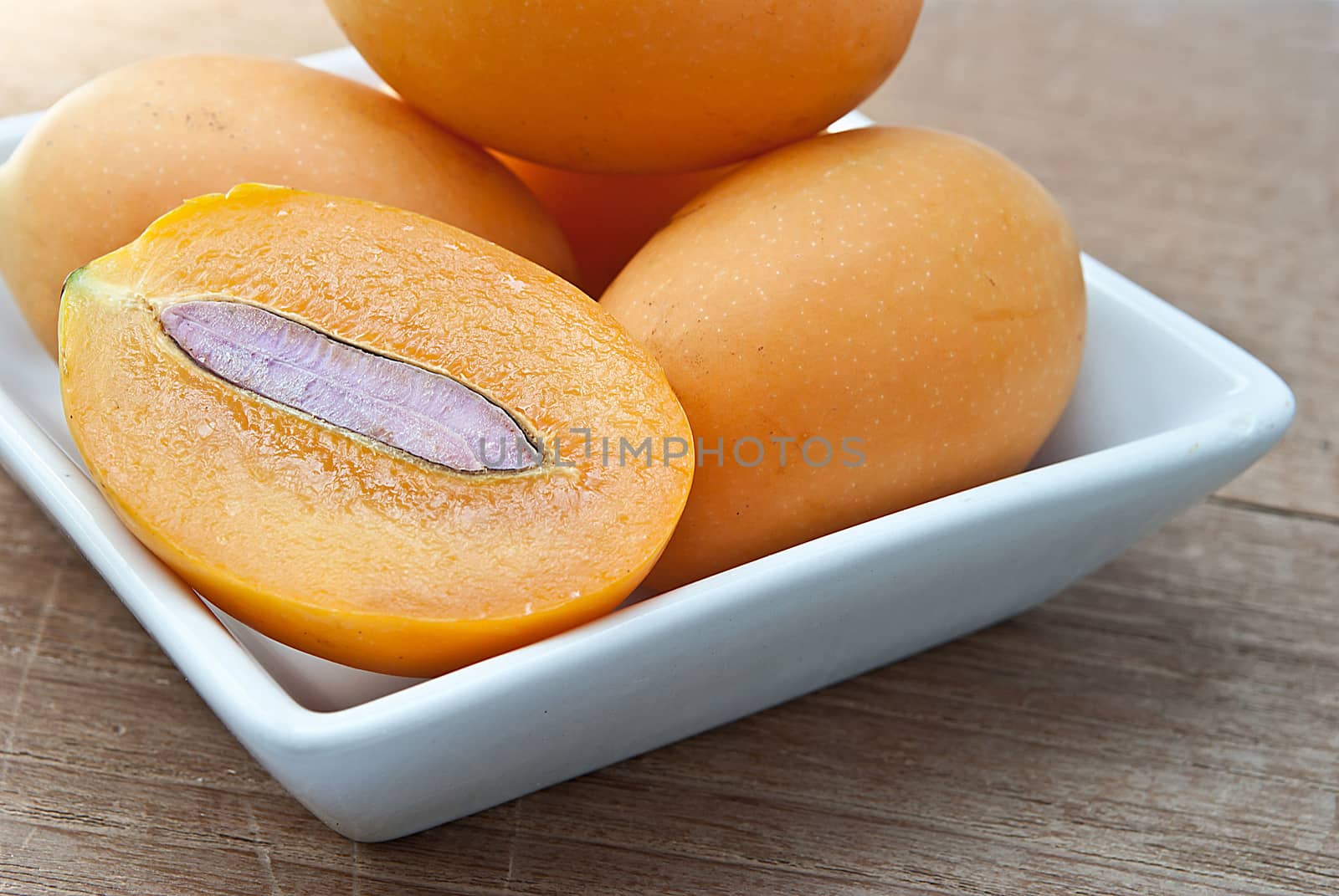 Sweet Marian plum fruit in bowl on wooden background (Mayongchid Maprang Marian Plum and Plum Mango,thailand).