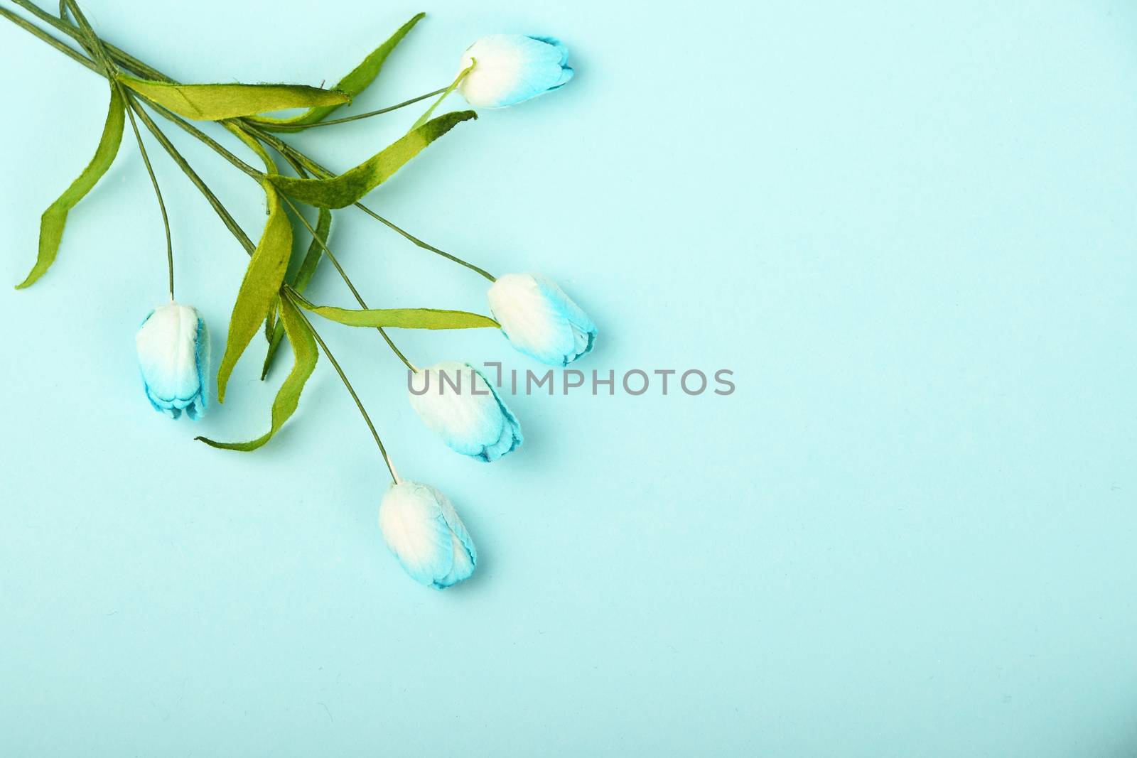 One tiny tulip mulberry paper flowers small bouquet in corner on tender blue background