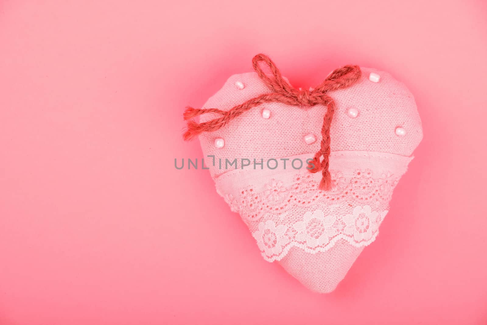 Valentine template, handmade pink toy textile lace heart with burlap jute bow, beads and copy space on paper background