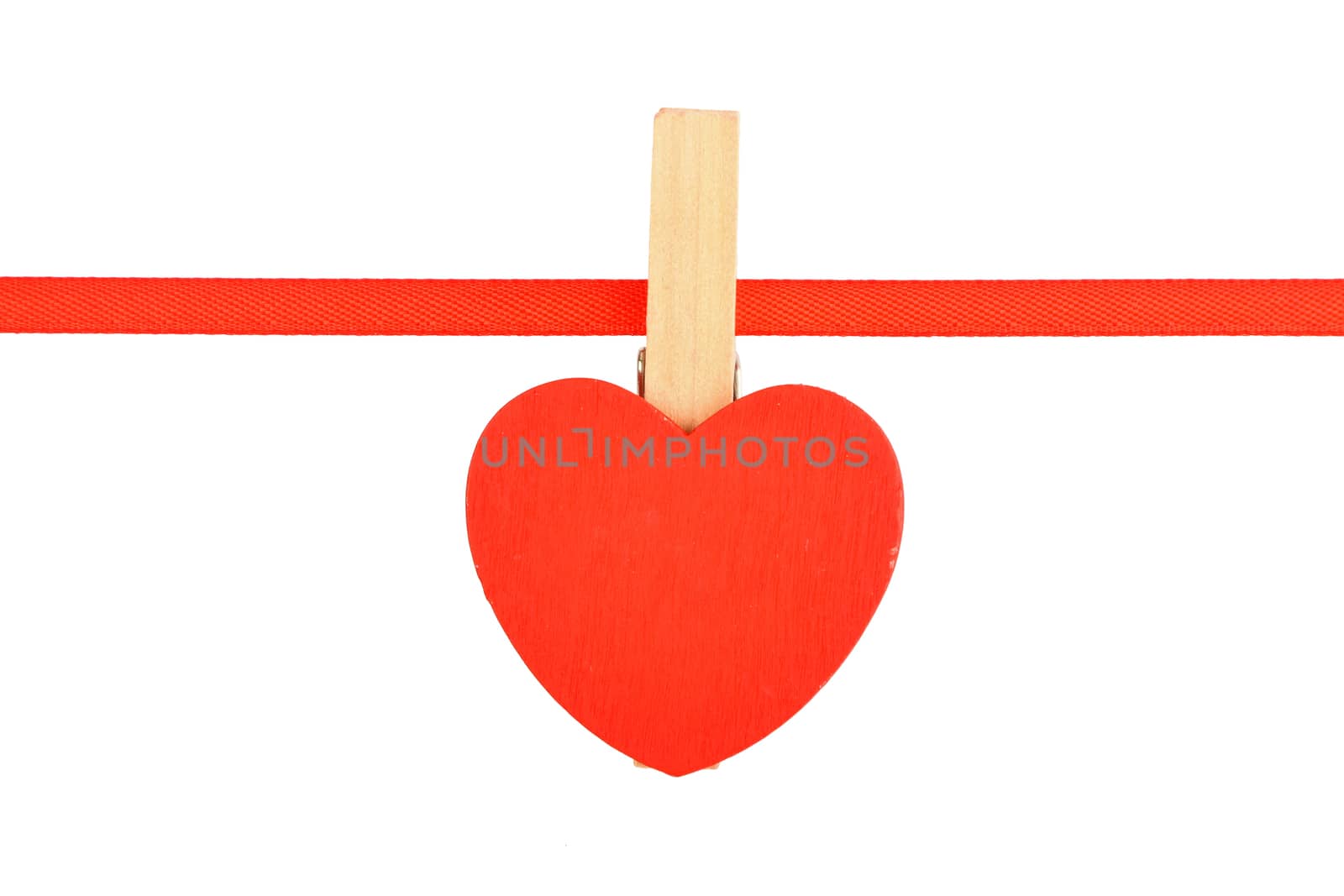 Red painted wooden heart with clothes pin on textile ribbon isolated on white background