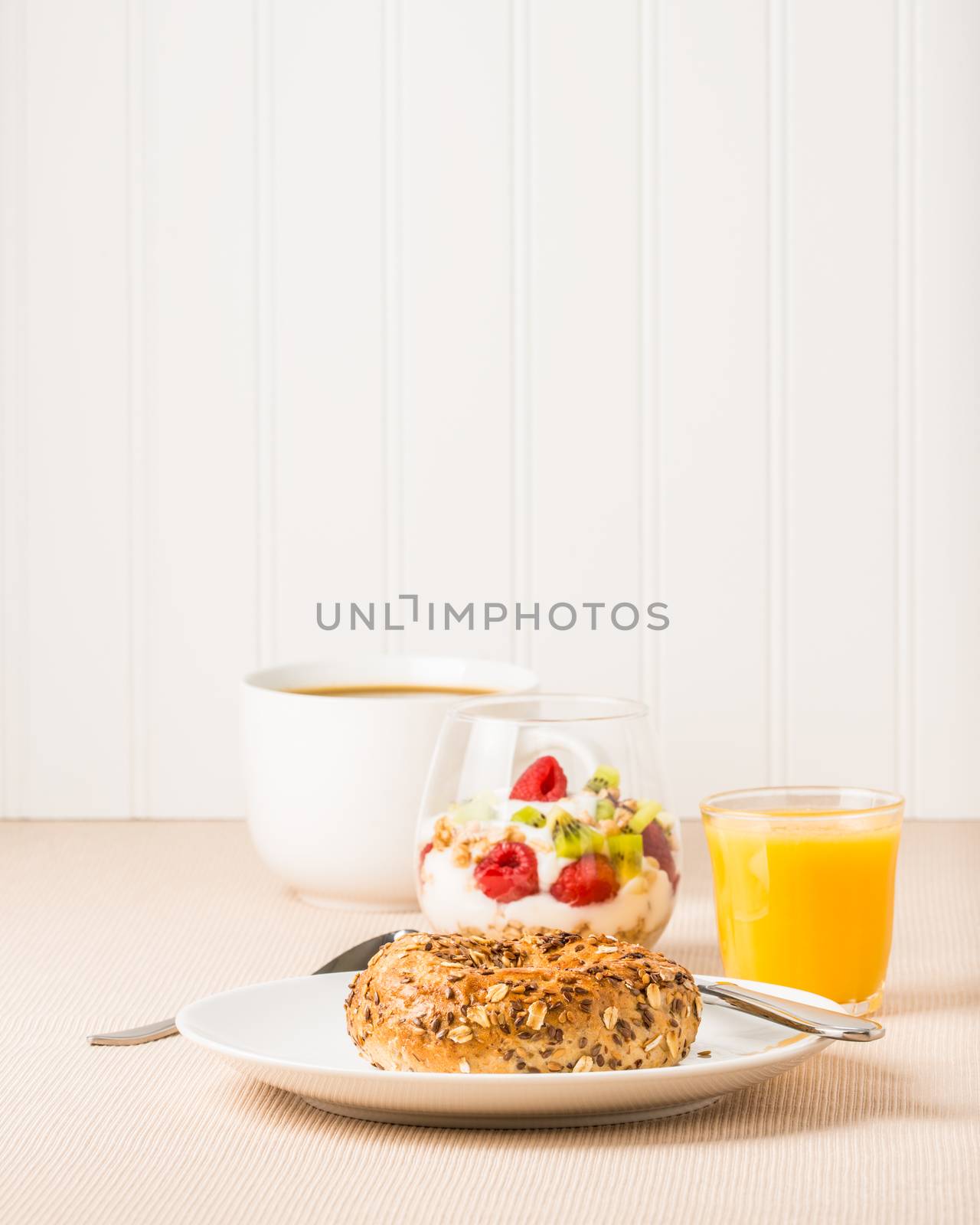 Simple healthy breakfast of a muesli bagel with coffee and a fruit parfait.