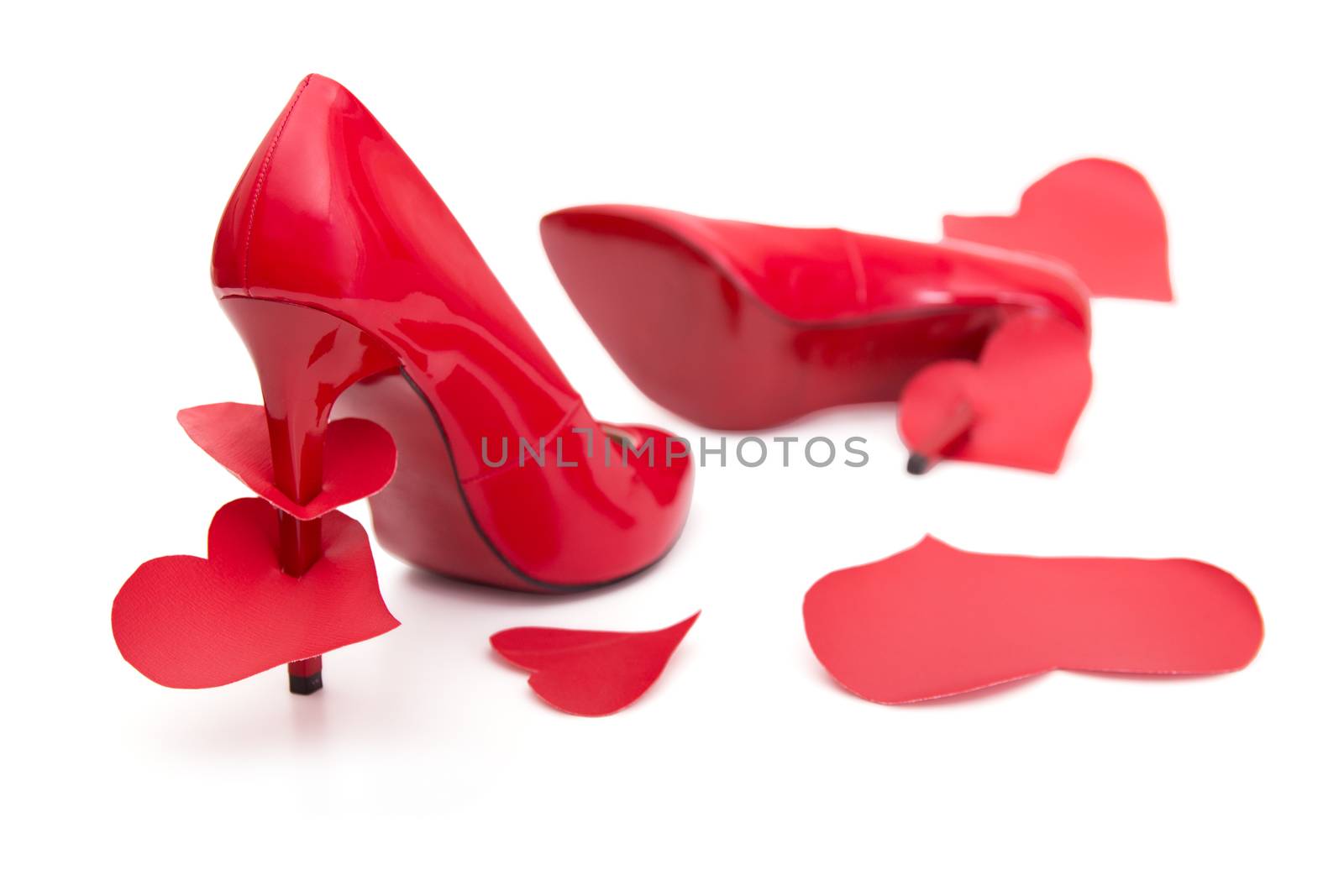 Red shoes with a high heel and stomped and strung on a hairpin of the heart on a white background