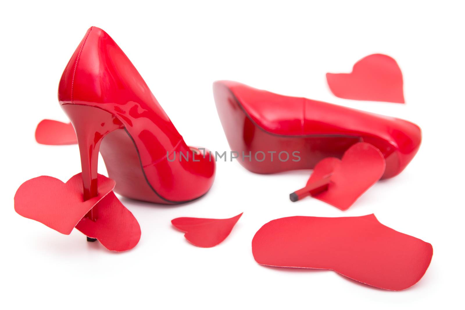 Red shoes with a high heel and stomped and strung on a hairpin of the heart on a white background