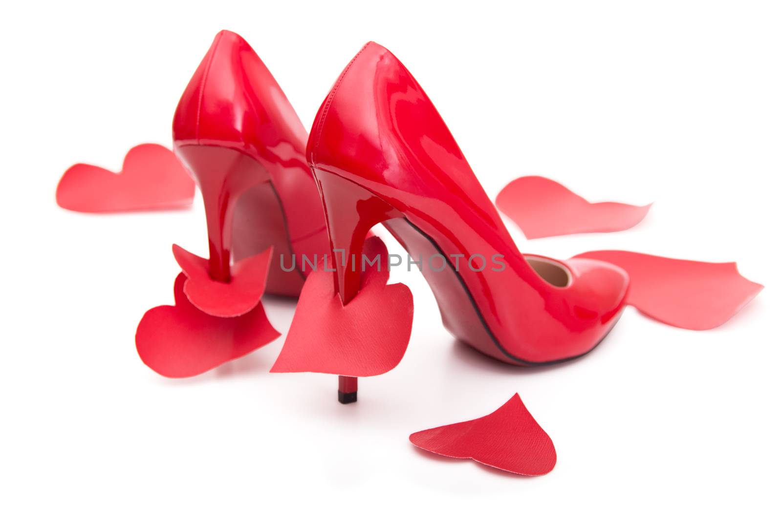 Red shoes with a high heel and stomped and strung on a hairpin of the heart on a white background