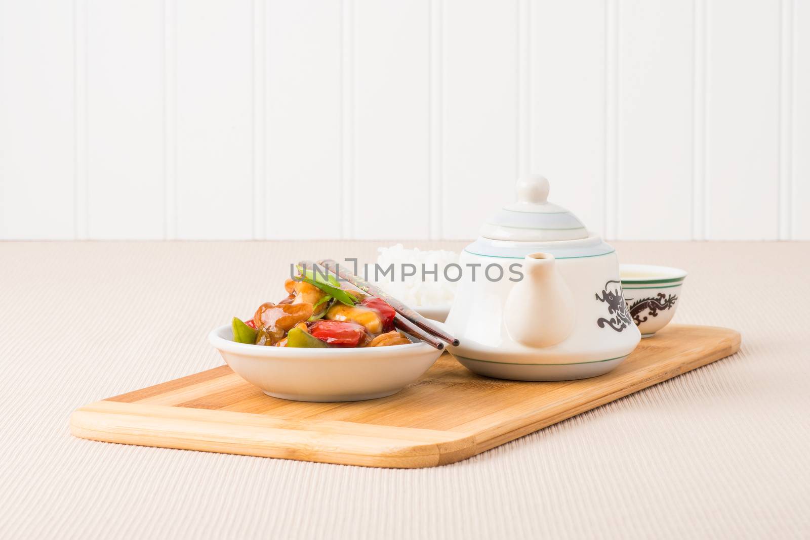 Bowl of oriental cashew chicken served with rice and chinese tea.