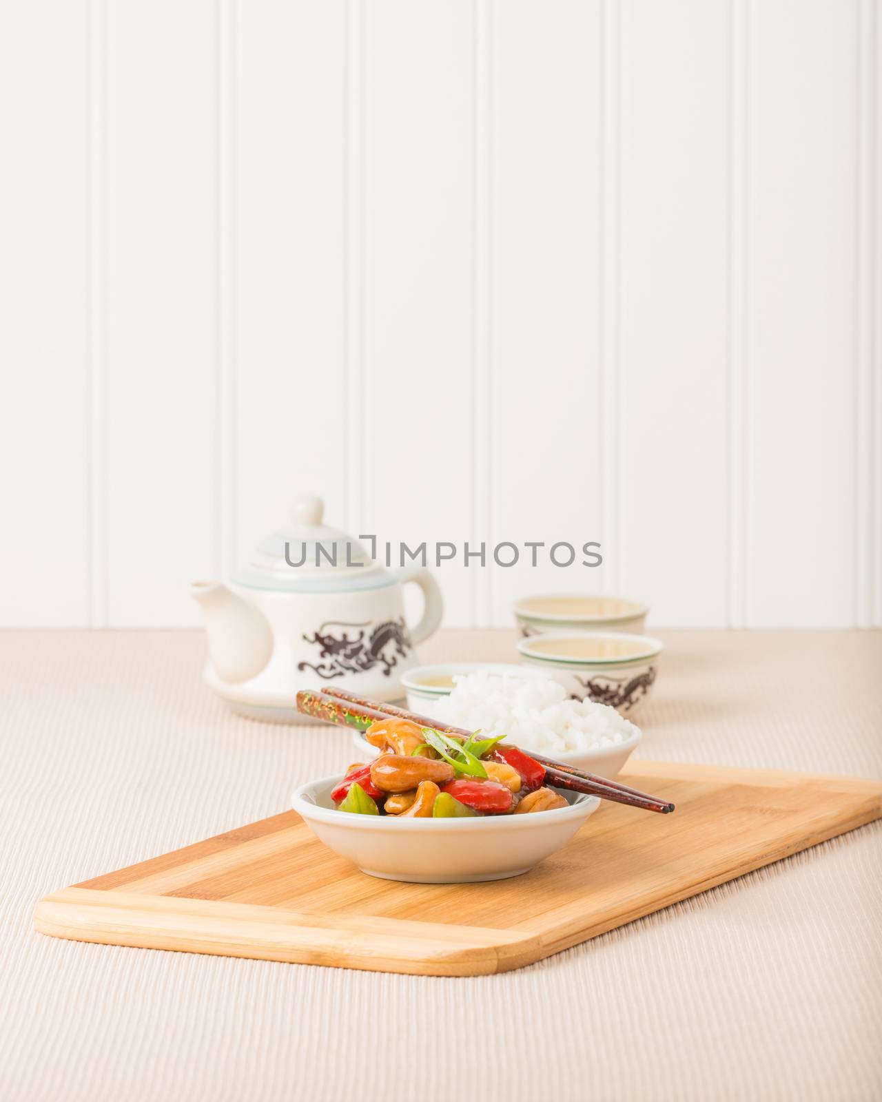 Bowl of Chinese cashew chicken served with white rice and tea.