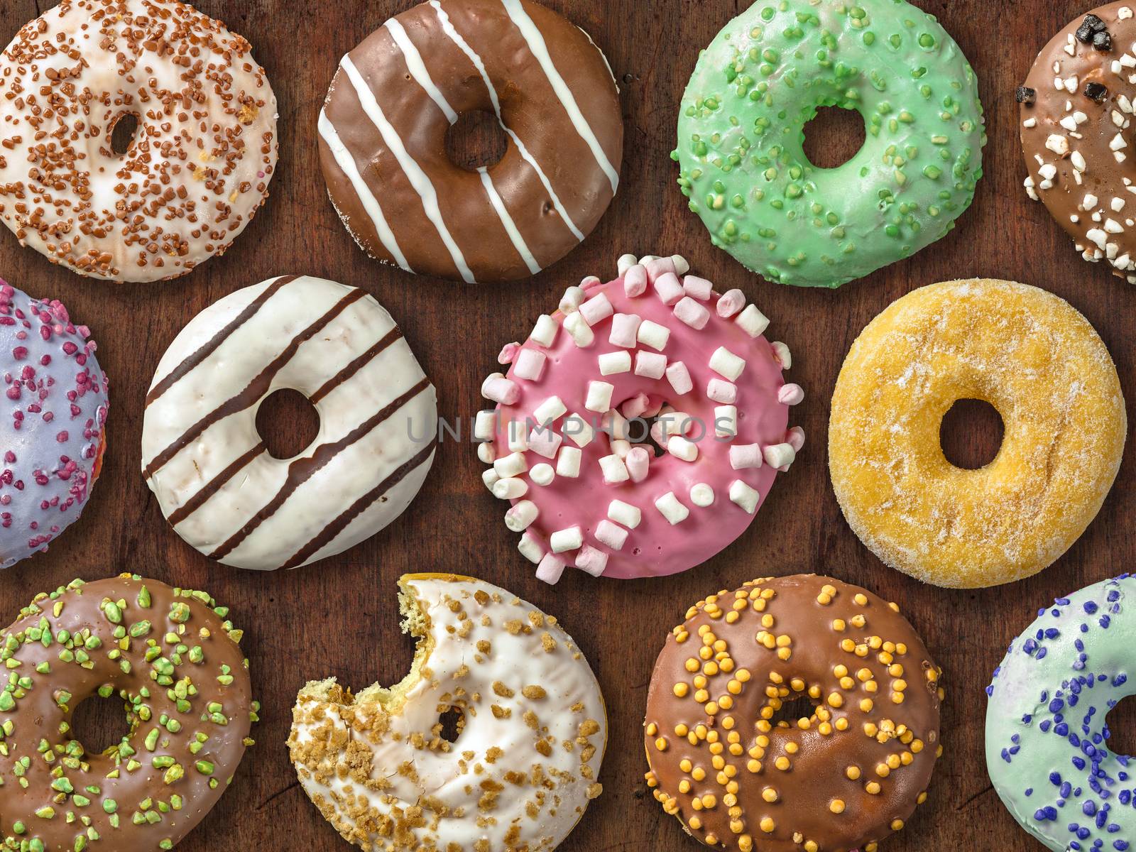 Photo of twelve different donuts over wood background.