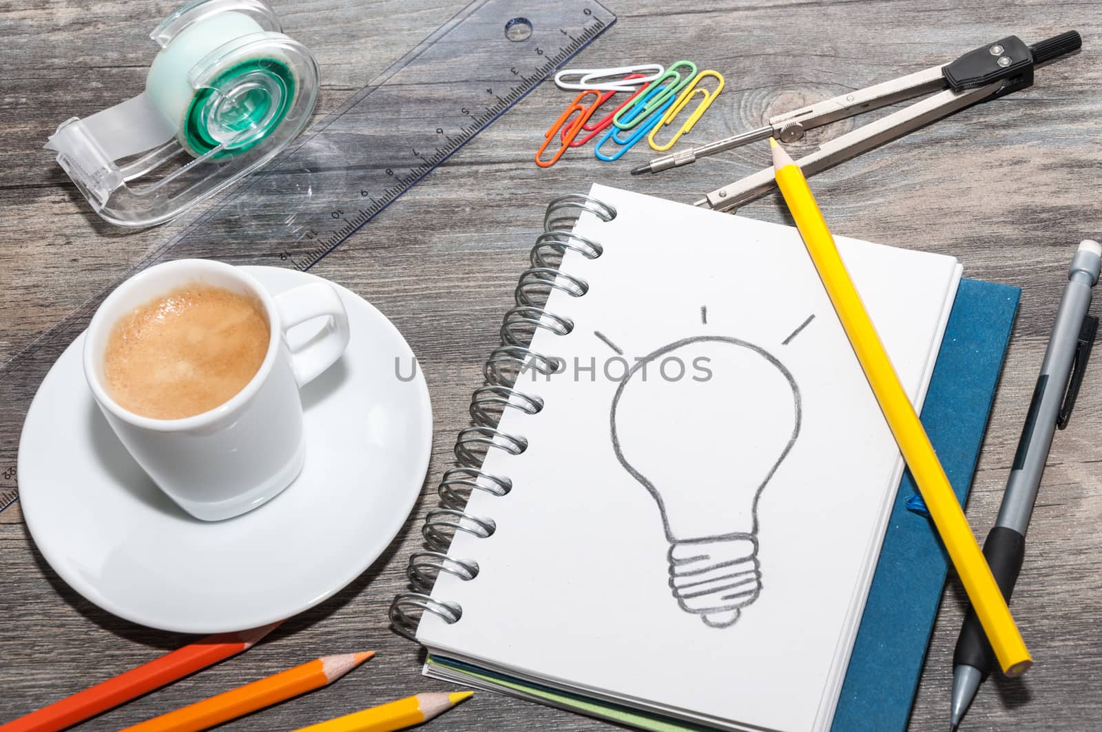 Office supplies, an open book with a drawing of a light bulb and a coffee