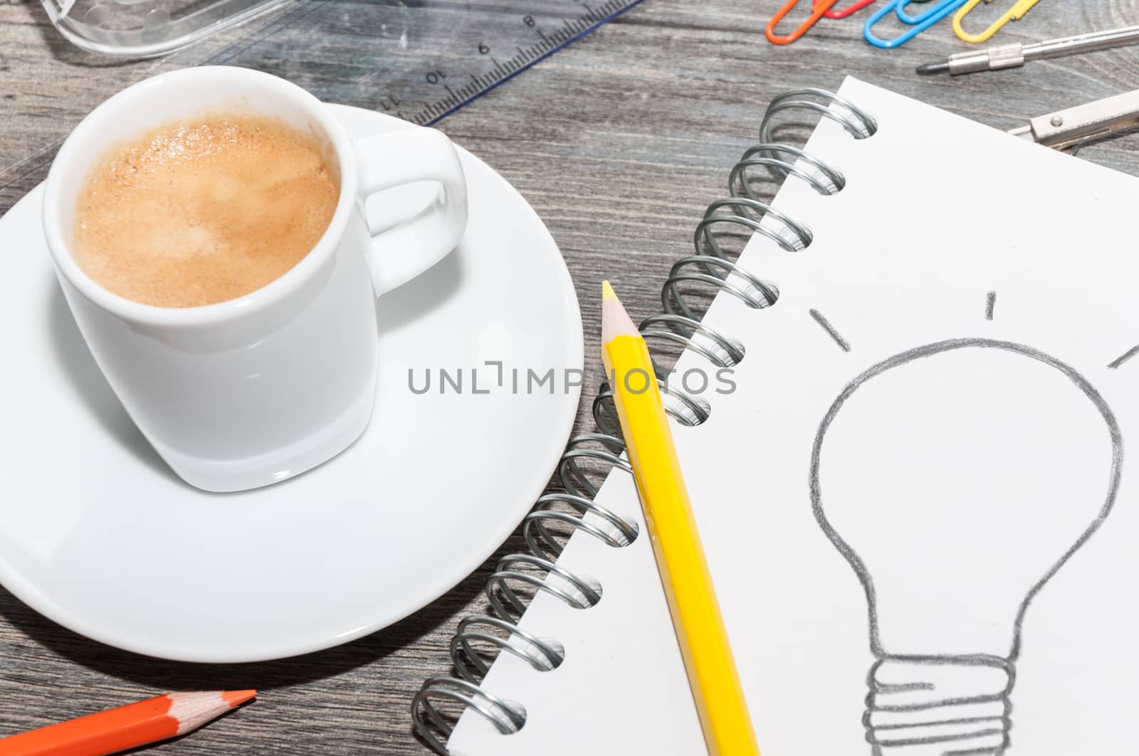 Office supplies, an open book with a drawing of a light bulb and a coffee