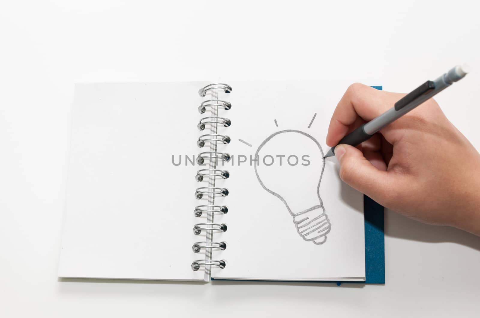 A hand drawing a light bulb in an open book