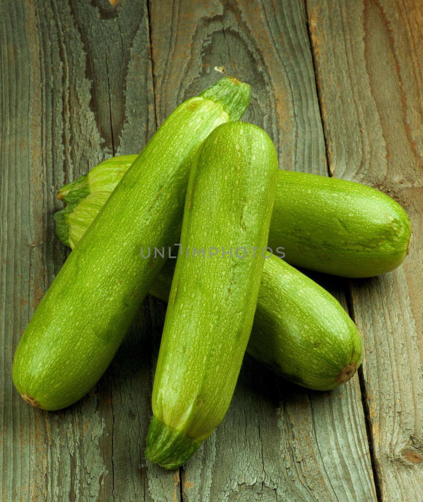 Heap of Four Fresh Raw Zucchini closeup on Rustic Wooden background