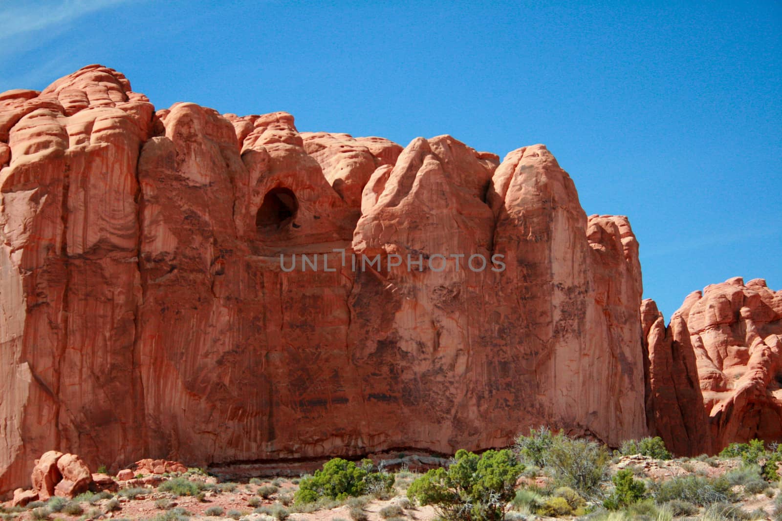A red rock formation with a cave carved out of Entrada Sandstone in Arches National Park near Moab Utah.