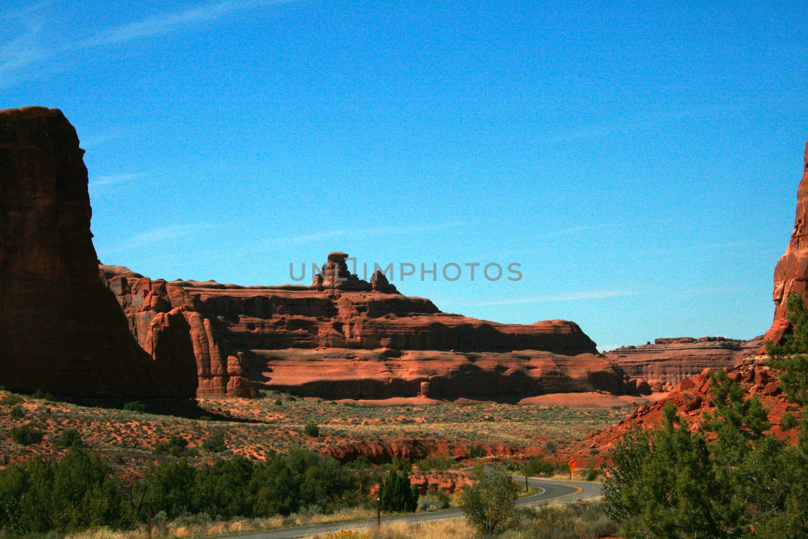 A Utah highway leads visitors to marvelous wonders of red stone in Arches National Park, USA.