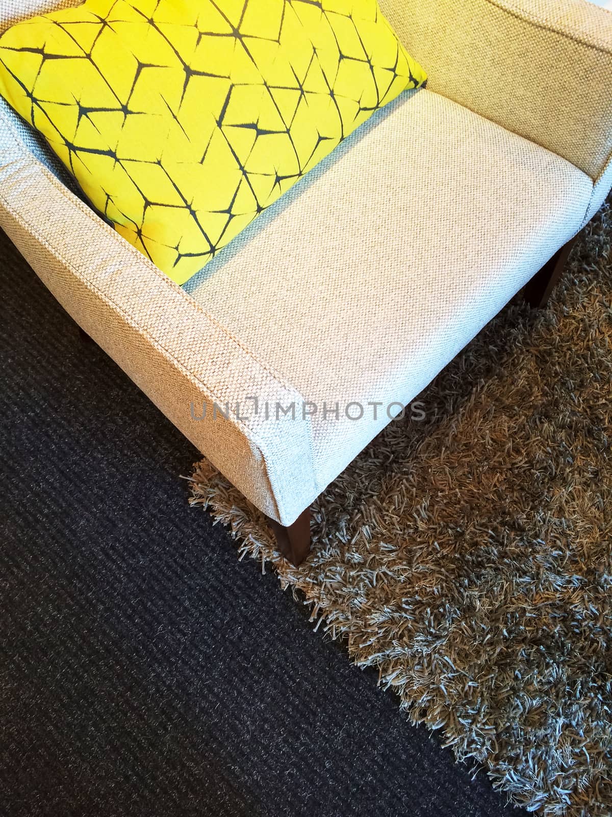 Armchair on a fluffy carpet, decorated with yellow cushion.