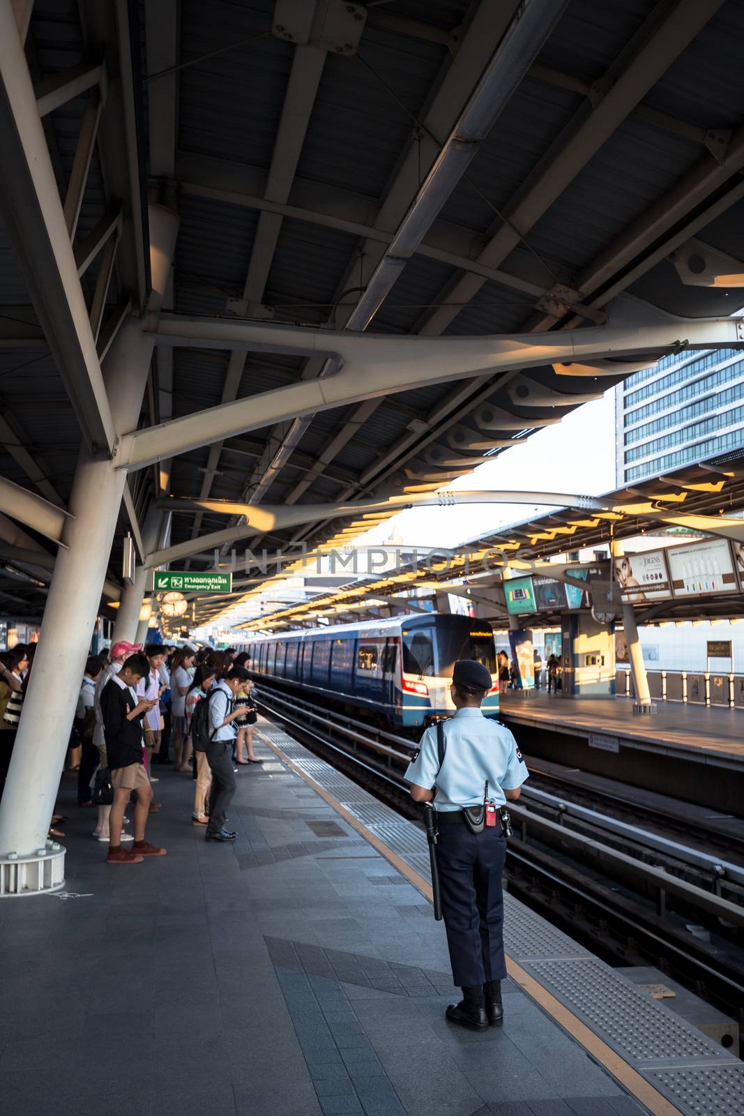 Bangkok, Thailand - January 18, 2016 : Security guard watching people while they waiting for the train to come to ensure safety of the passengers at BTS National Stadium station in the rush hour. Daily passengers of BTS skytrain is around 700,000