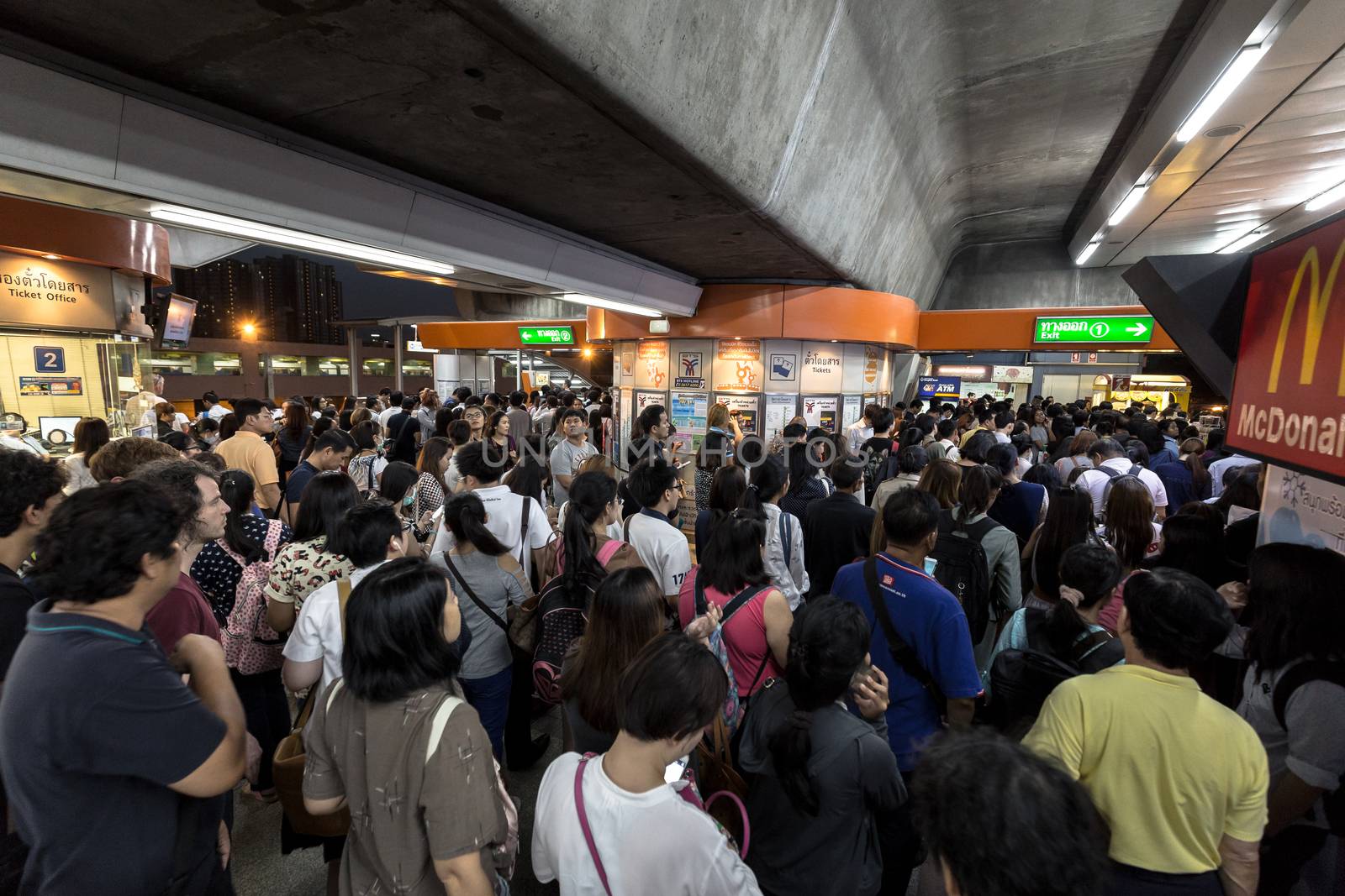 Bangkok, Thailand - January 18, 2016 : Crowd of people walking out from the BTS Mo Chit station to the road in the rush hour at night with the ticket machine in the center. Daily passengers of BTS skytrain is around 700,000