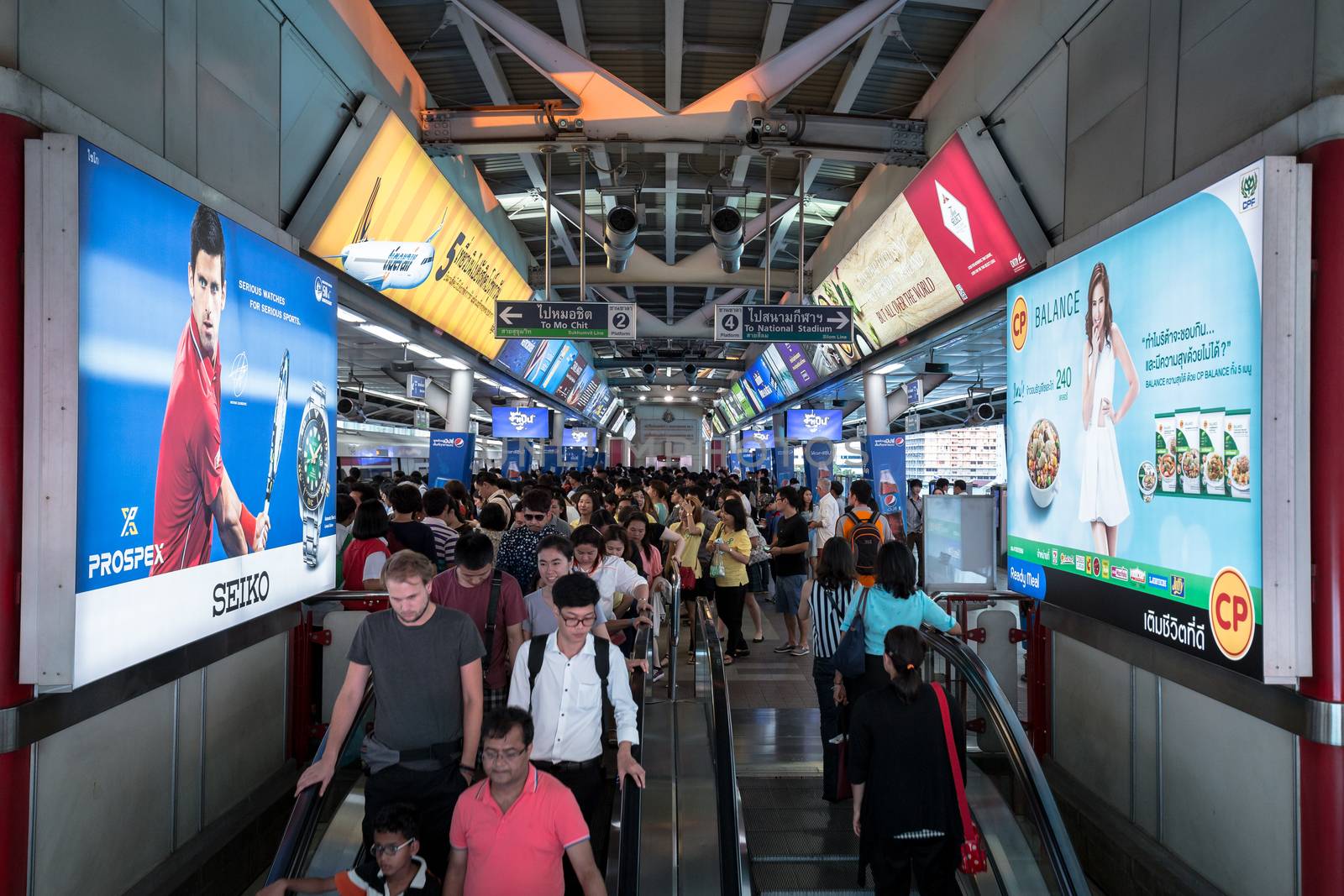 Bangkok, Thailand - January 18, 2016 : crowd of people at BTS Siam station some people waiting for the train and some people using the escalator that has advertising along the way in the rush hour evening. Daily passengers of BTS skytrain is around 700,000