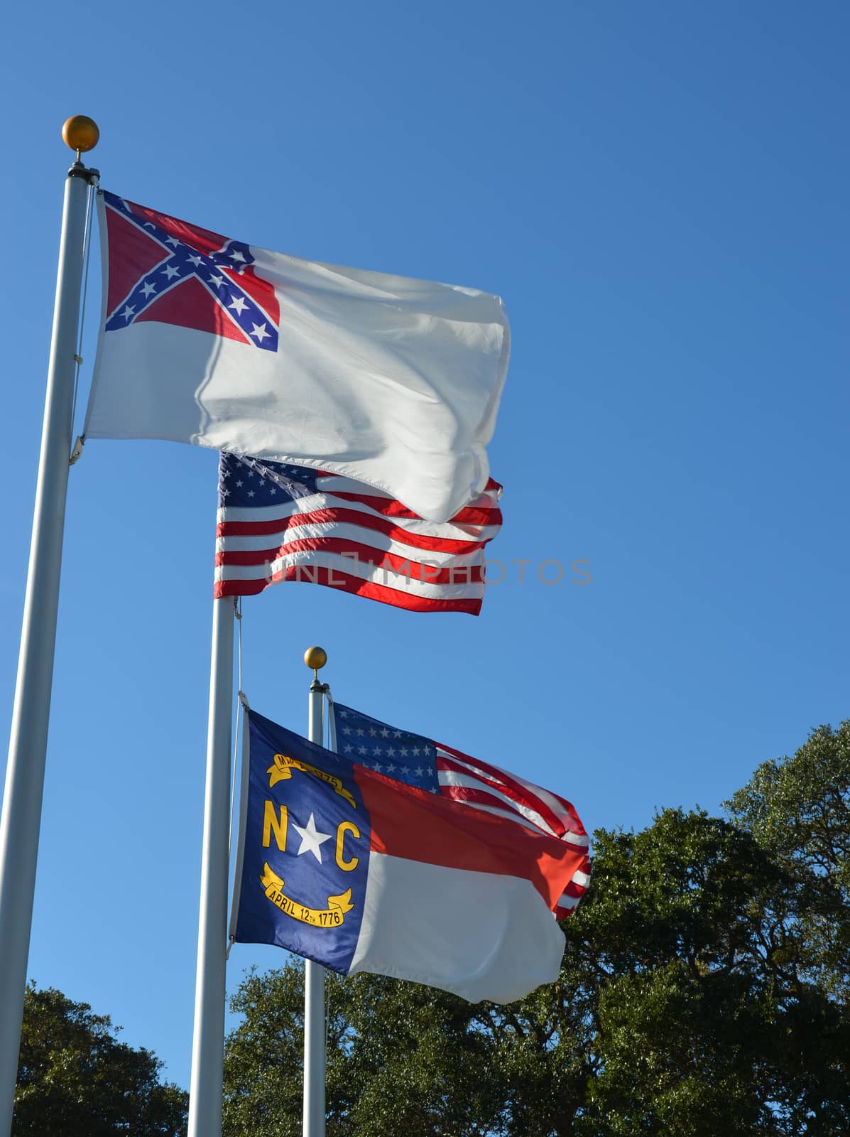 American flag flying in the wind, along with a North Carolina and a historic confederate flag.