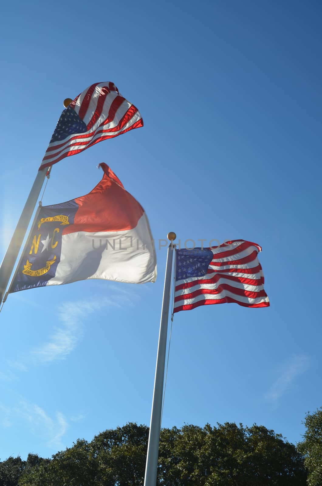American flag flying in the wind along with a North Carolina flag