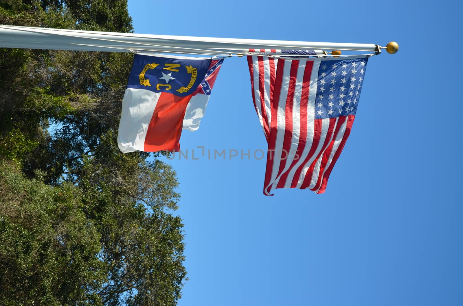 American flag flying in the wind and a North Carolina Flag next to it.