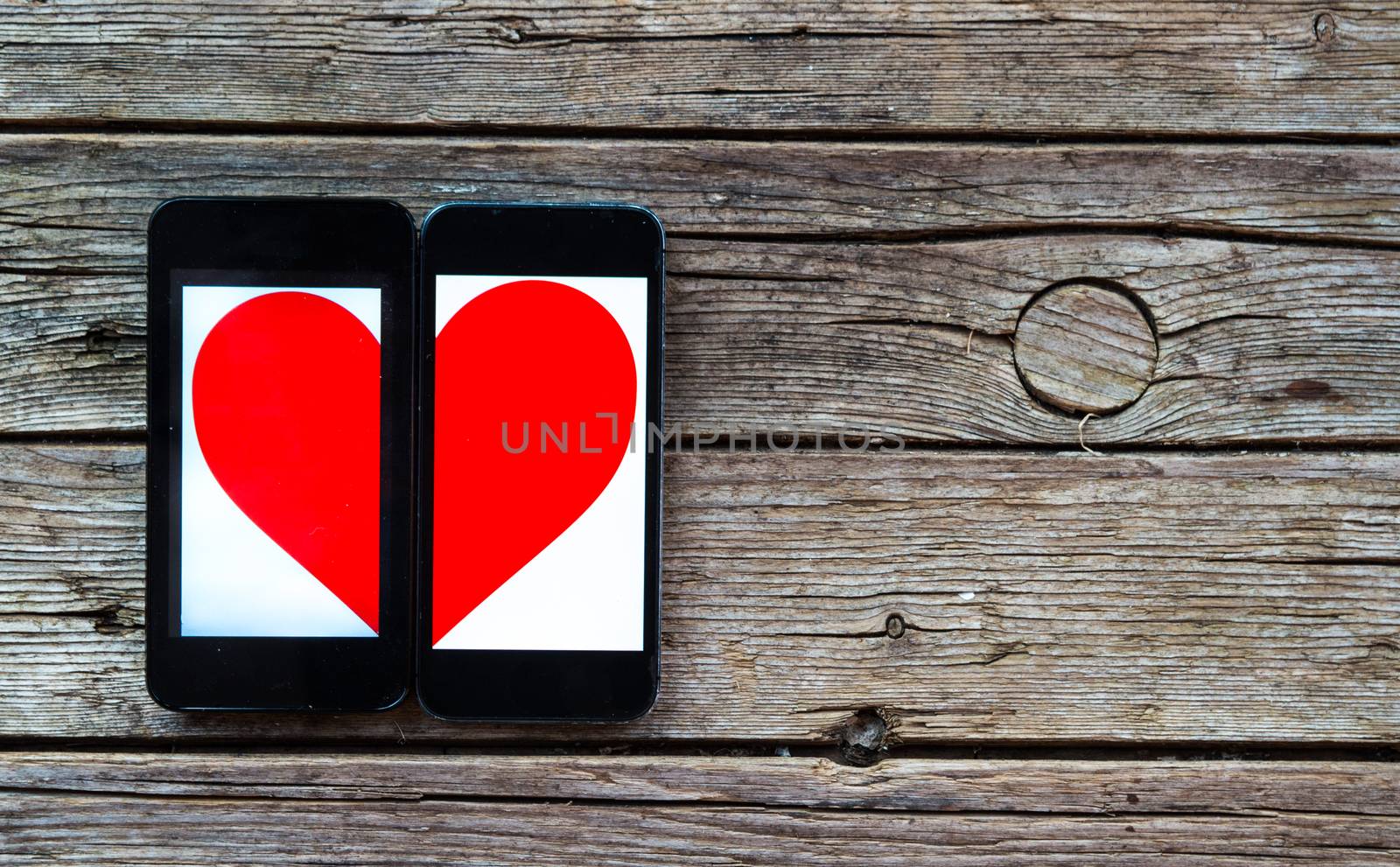 Two Cellphones With Half Heart Symbol on wooden background