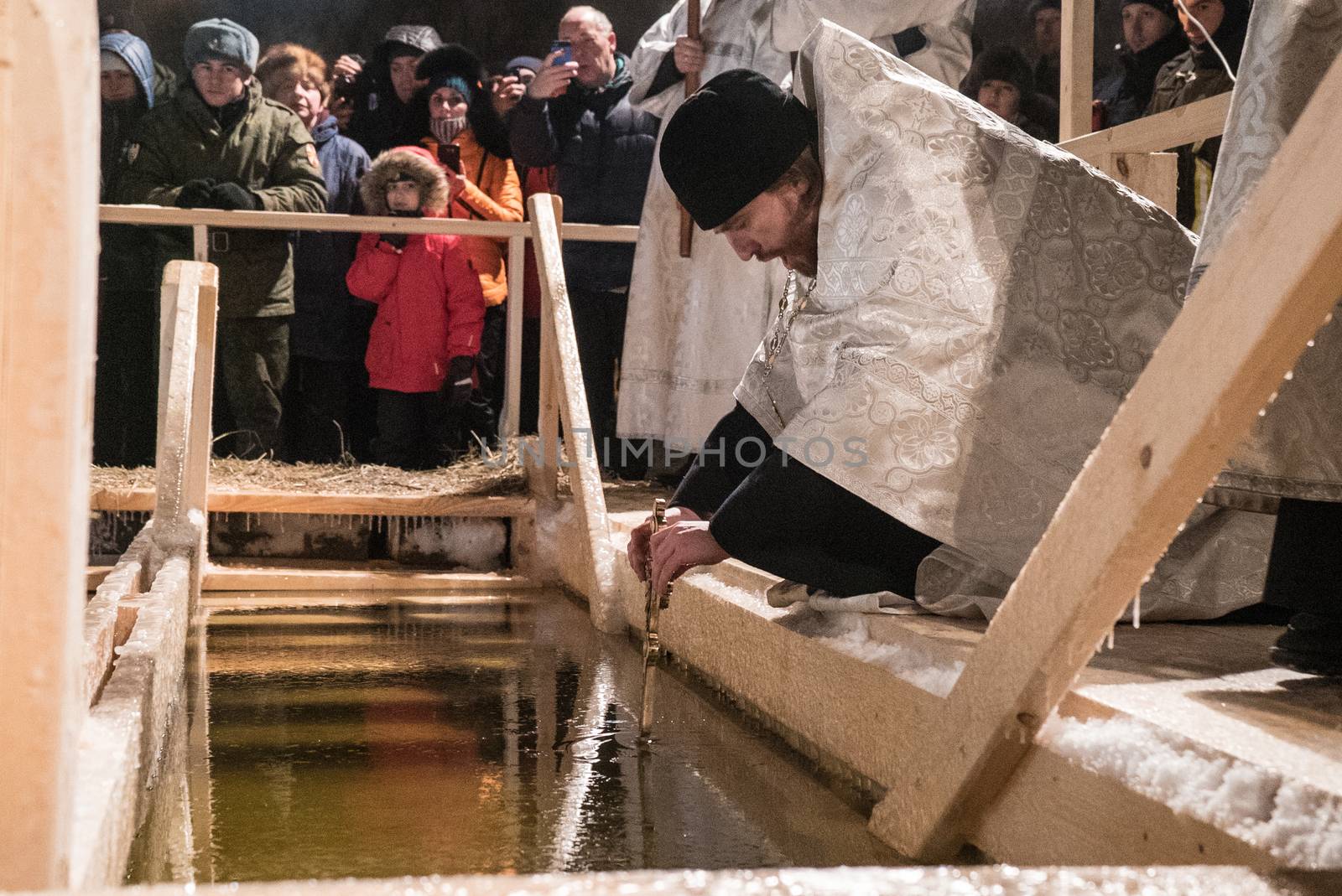 RUSSIA, Moscow: A priest blesses the water on January 19, 2016 in Moscow, as part of Epiphany ceremonies.Among Orthodox Christians, the feast of Epiphany celebrates the day the spirit of God descended upon believers in the shape of a dove during Jesus Christ's baptism in the river Jordan. At midnight, worshippers walked in procession from one of Moscow's Orthodox temples to the lake. Tents for warming and changing clothes were arranged by military people and the Ministry of Emergency (EMERCOM). Women and little children entered the water at the temperature 10 degrees below zero. Some people stayed in water just a few seconds, others, praying, plunged several times. 