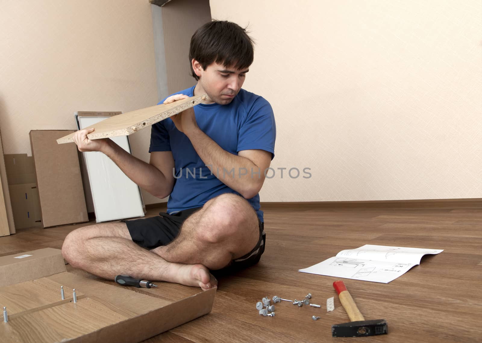 Young man puzzled aboutassembling flatpack closet