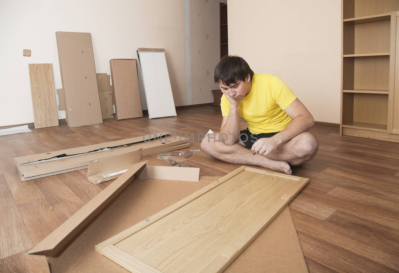 Young man puzzled about assembling flatpack closet