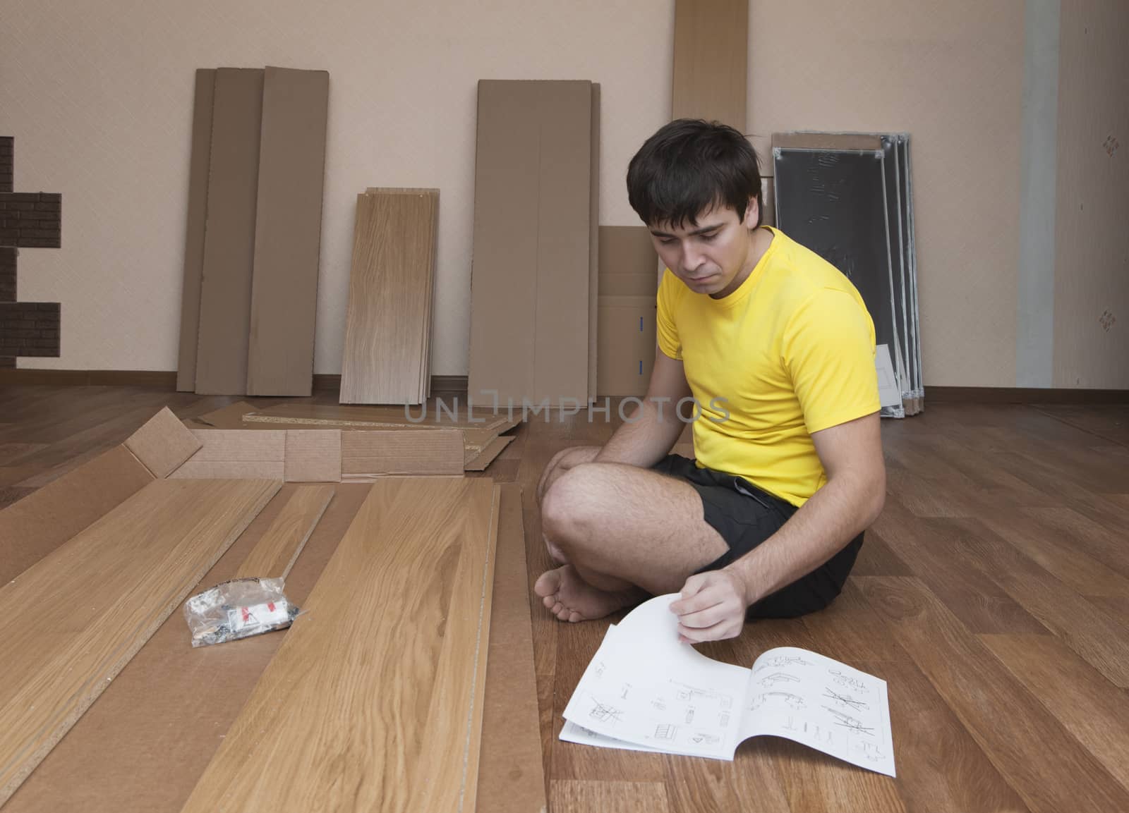 Young man sitting on floor assembling flatpack closet