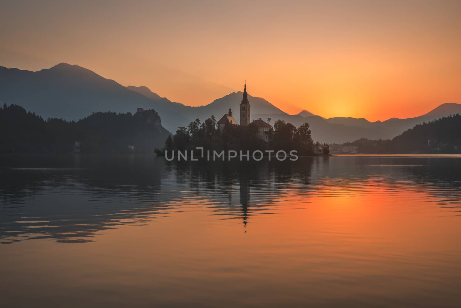 Little Island with Catholic Church in Bled Lake, Slovenia at Beautiful Colorful Sunrise with Castle and Mountains in Background