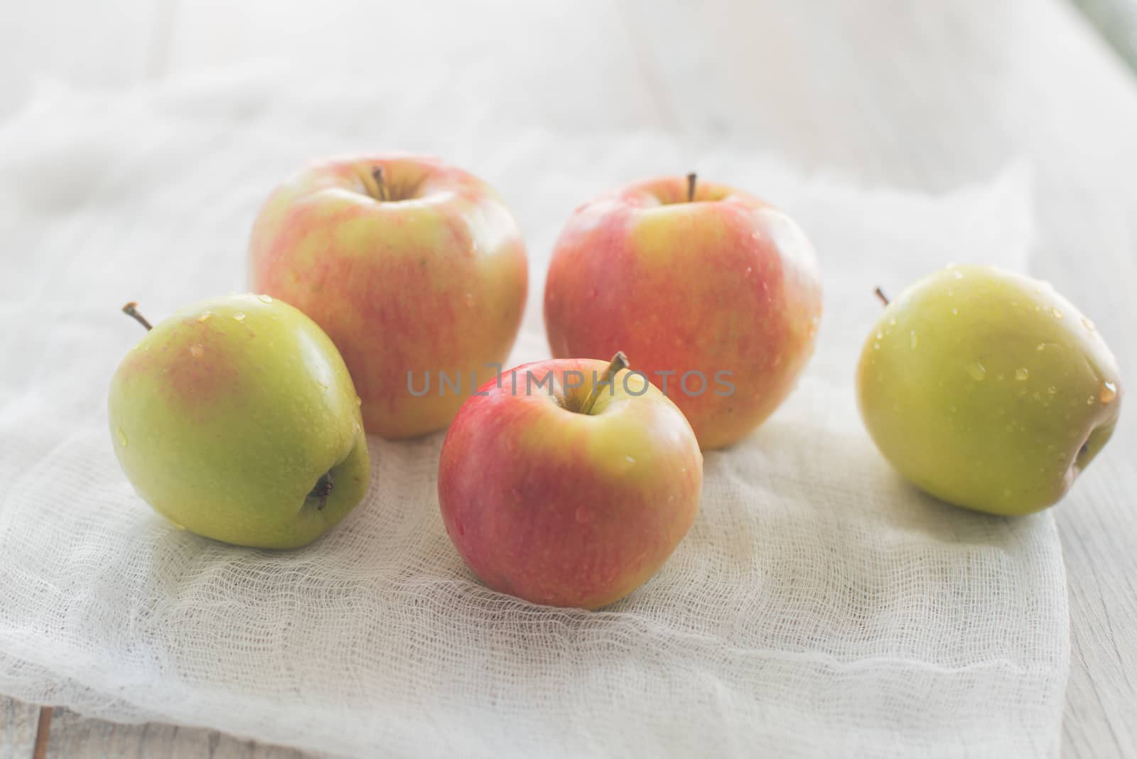 Five apples lay on the white textile