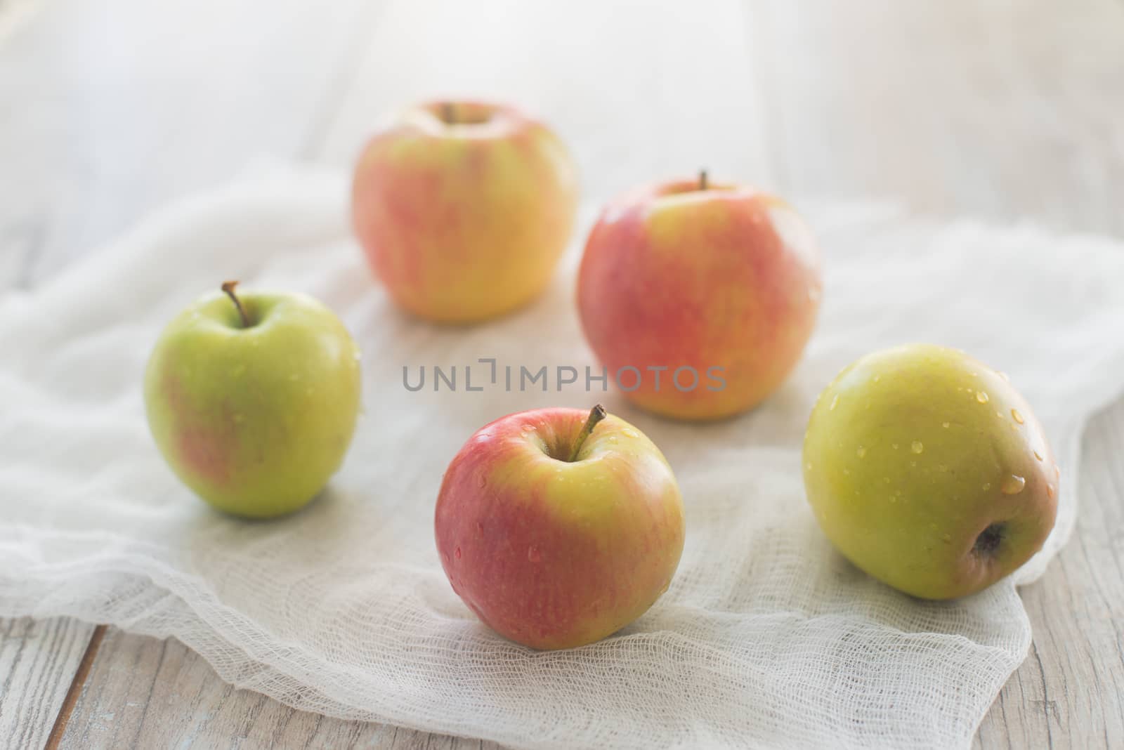 Five apples lay on the white textile