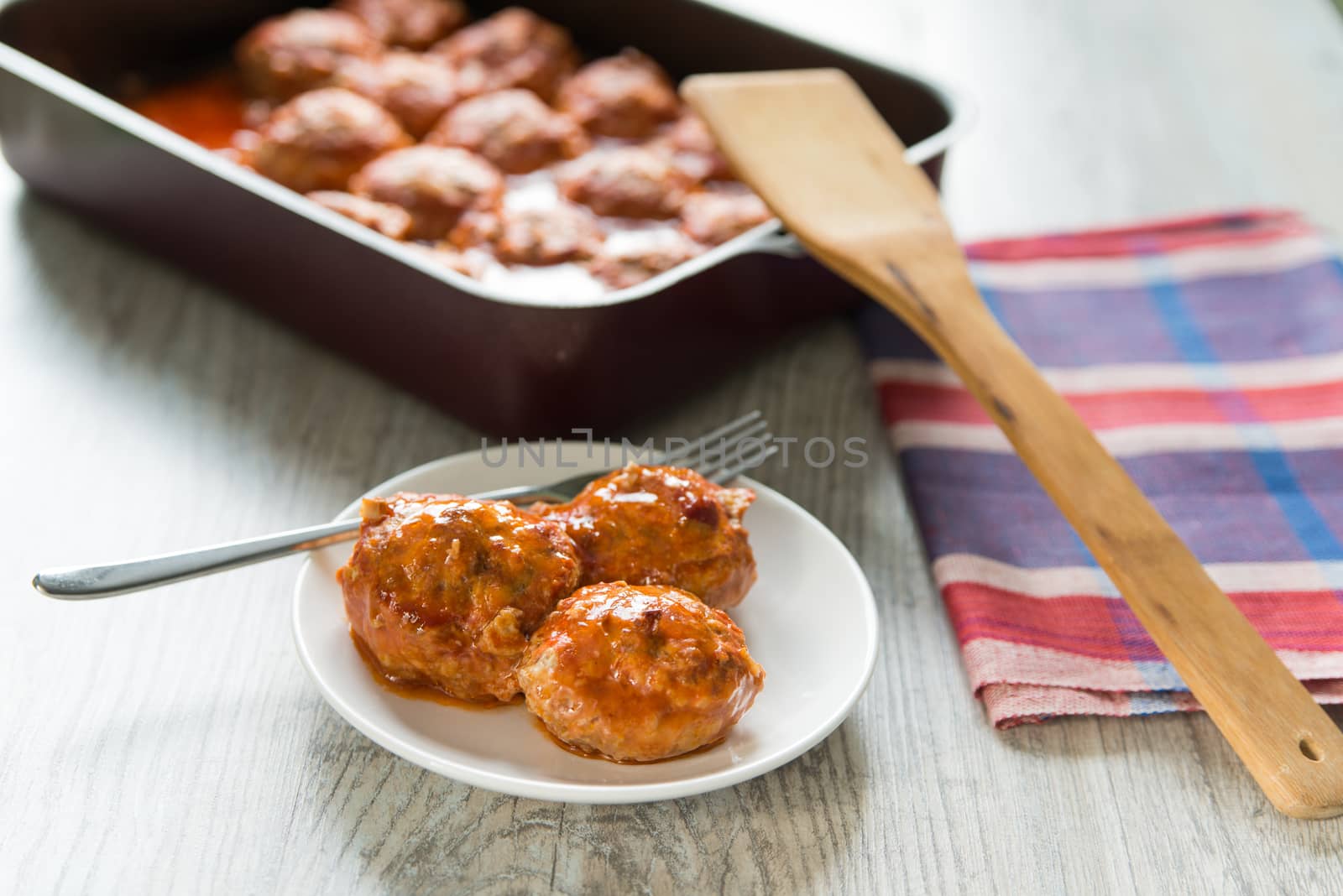 Portion of three meatballs on white plate by Linaga