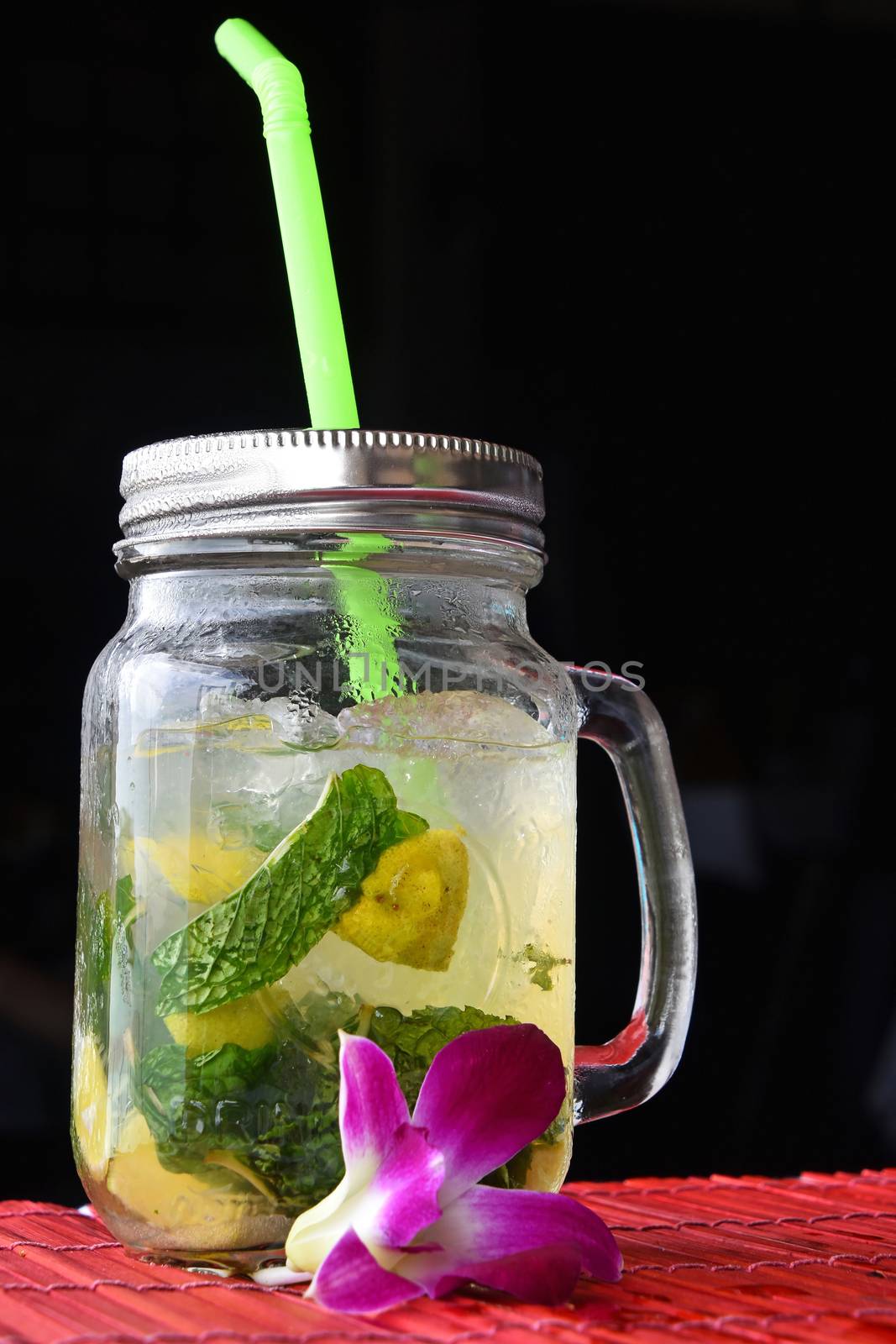 Big glass of mojito with orchid flower on black by BreakingTheWalls
