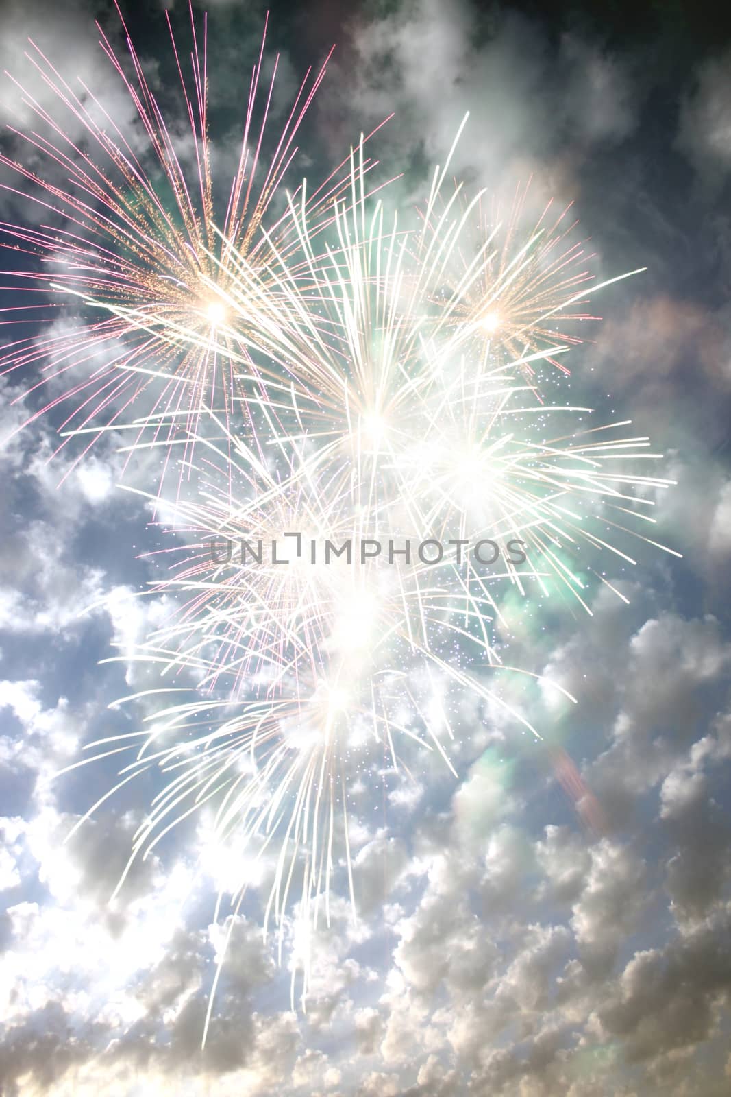 Fireworks exploding on the backdrop of a cloudy sky, during day time.