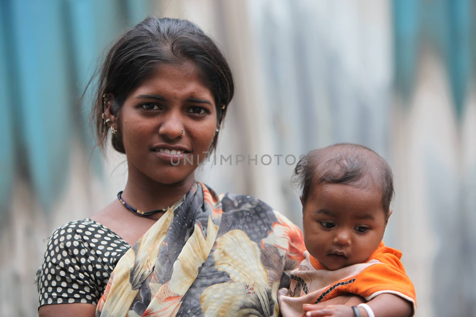 A portrait of a poor Indian lady in her late teens with her baby boy.