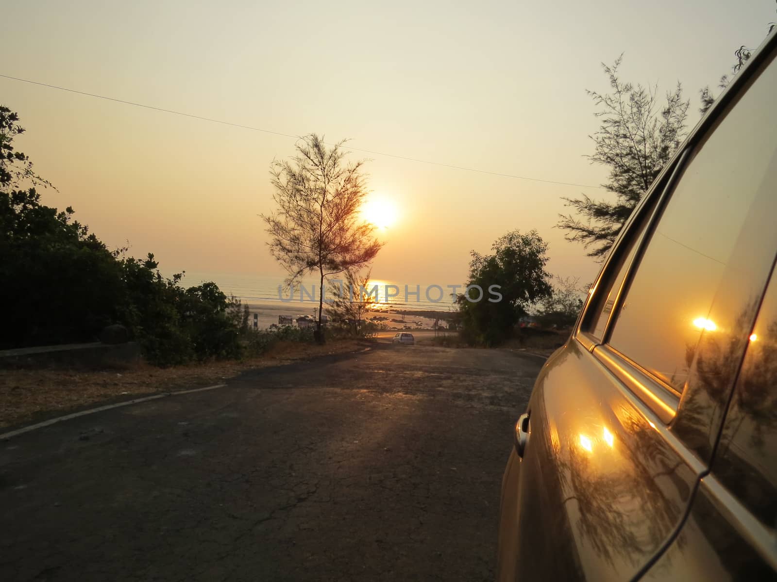 The reflection of the setting sun over a beach on the windows of a car.