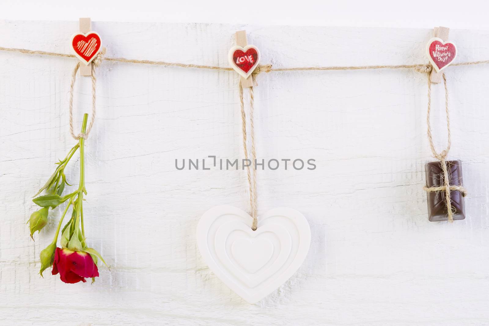 Red rose with white shape heart and chocolate on white wooden background