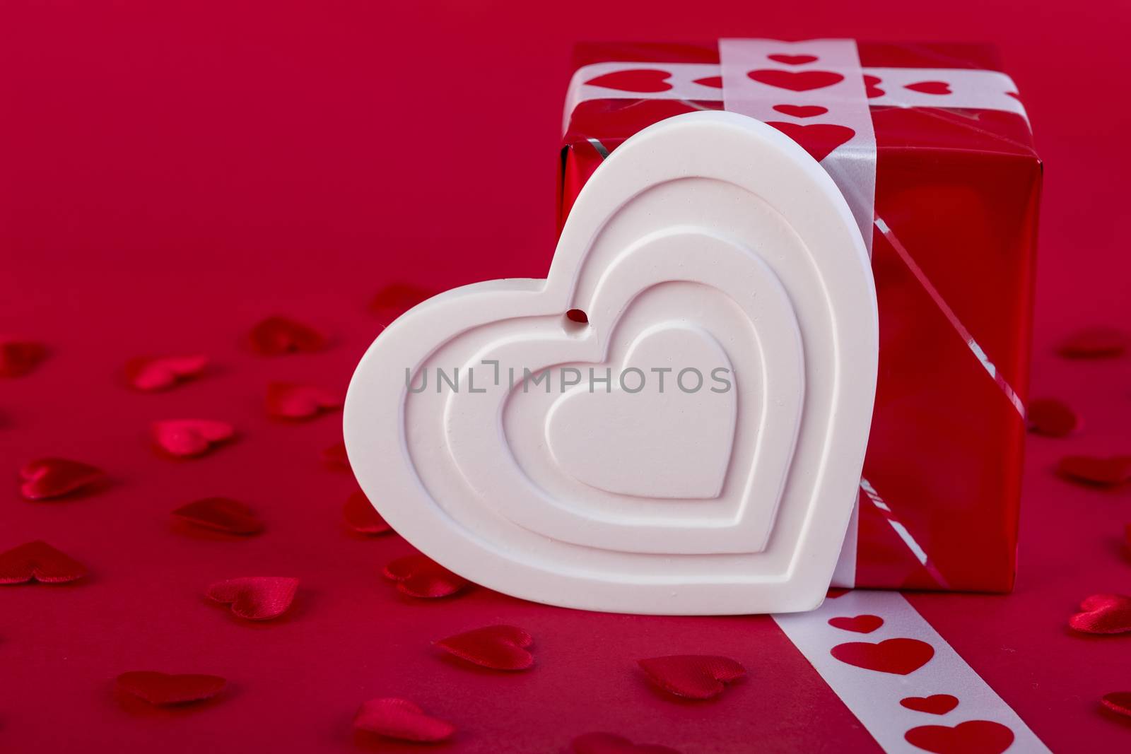 Red Holidays gift and heart on red background/ Valentines day background